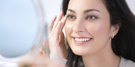 brunette woman smiling in hand mirror