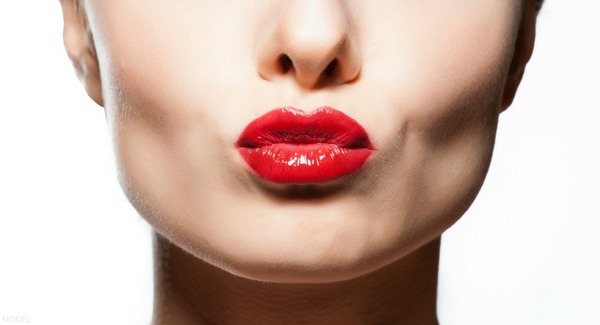 Lower half of model's face with perking lips red lipstick