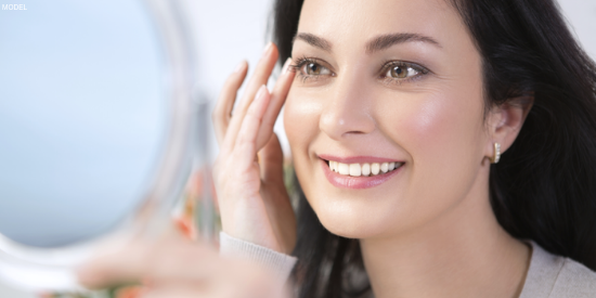 Woman admiring her eyes after eyelid surgery and dermal fillers