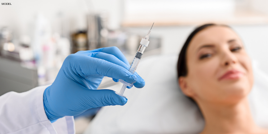 Patient staring at doctor's blue gloved hand, holding a syringe